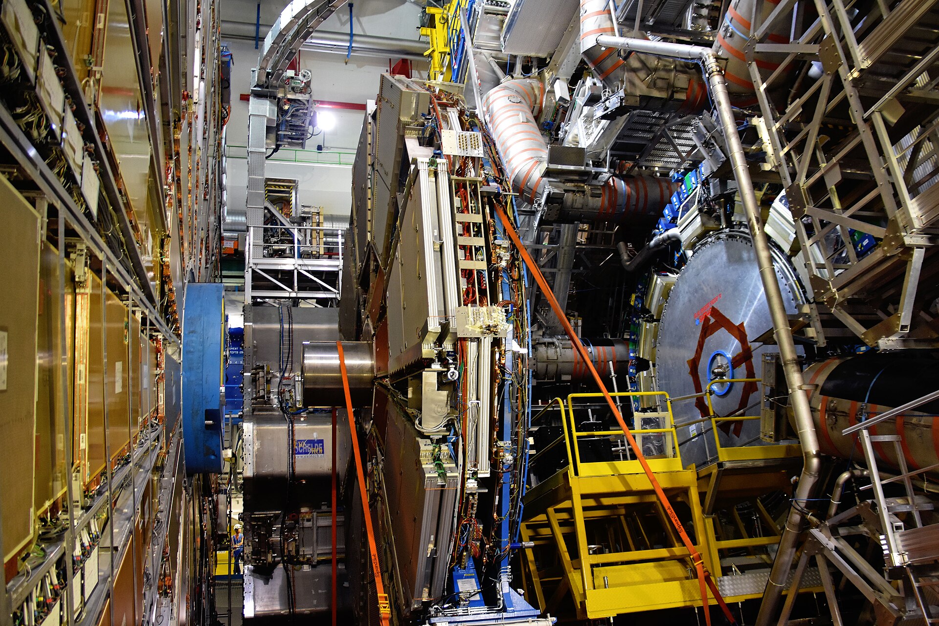 The vast ATLAS detector at CERN, a cathedral of steel and cabling built to catch the smallest pieces of matter there are, with a single worker tiny beside it
