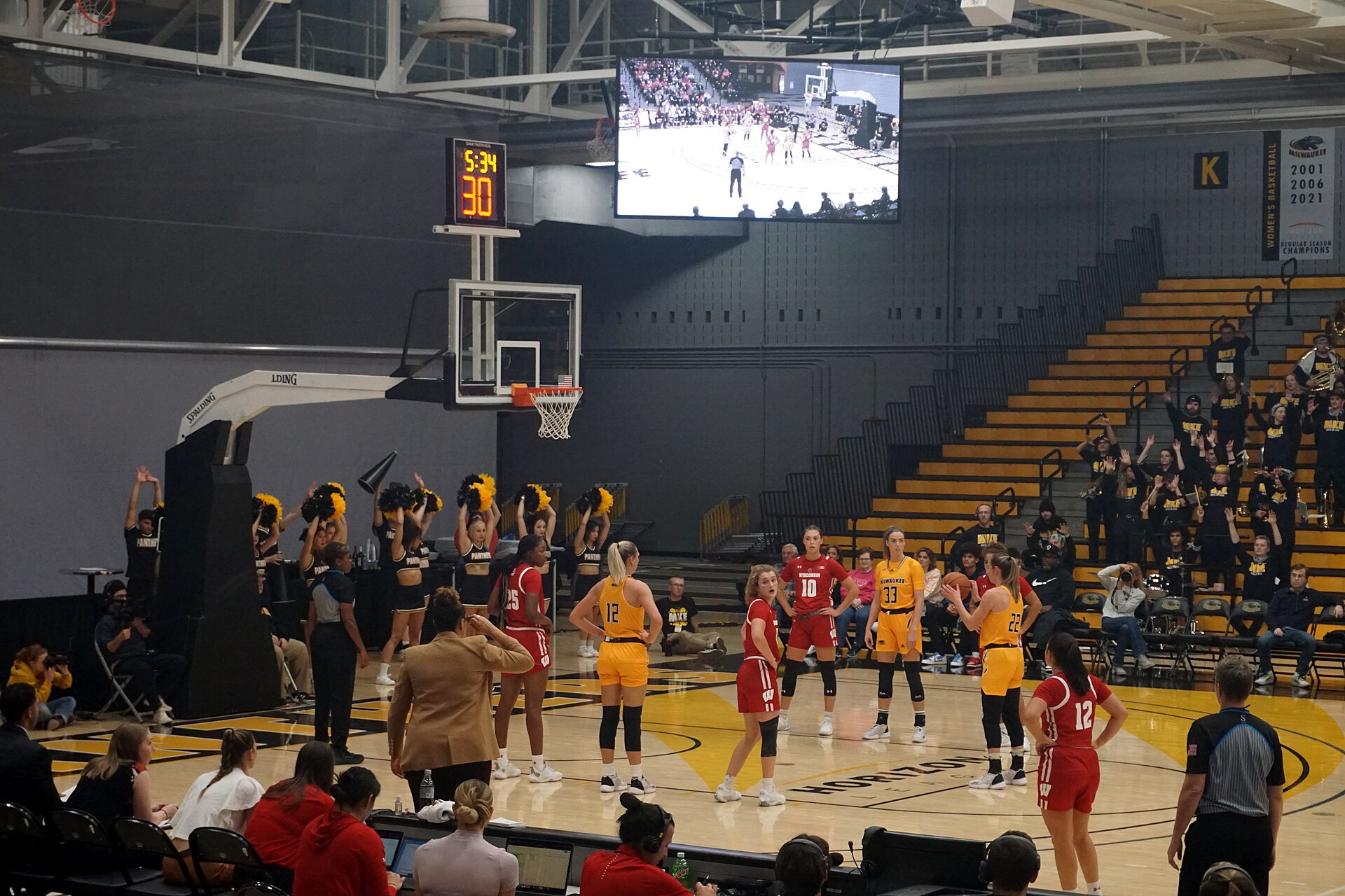 A basketball player at the free-throw line holding the ball ready to shoot, with the hoop across the court in front of her.