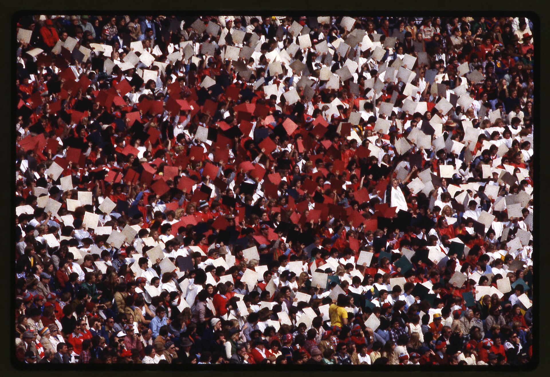 A stadium crowd seen from above, thousands upon thousands of people packed together, far too many to count