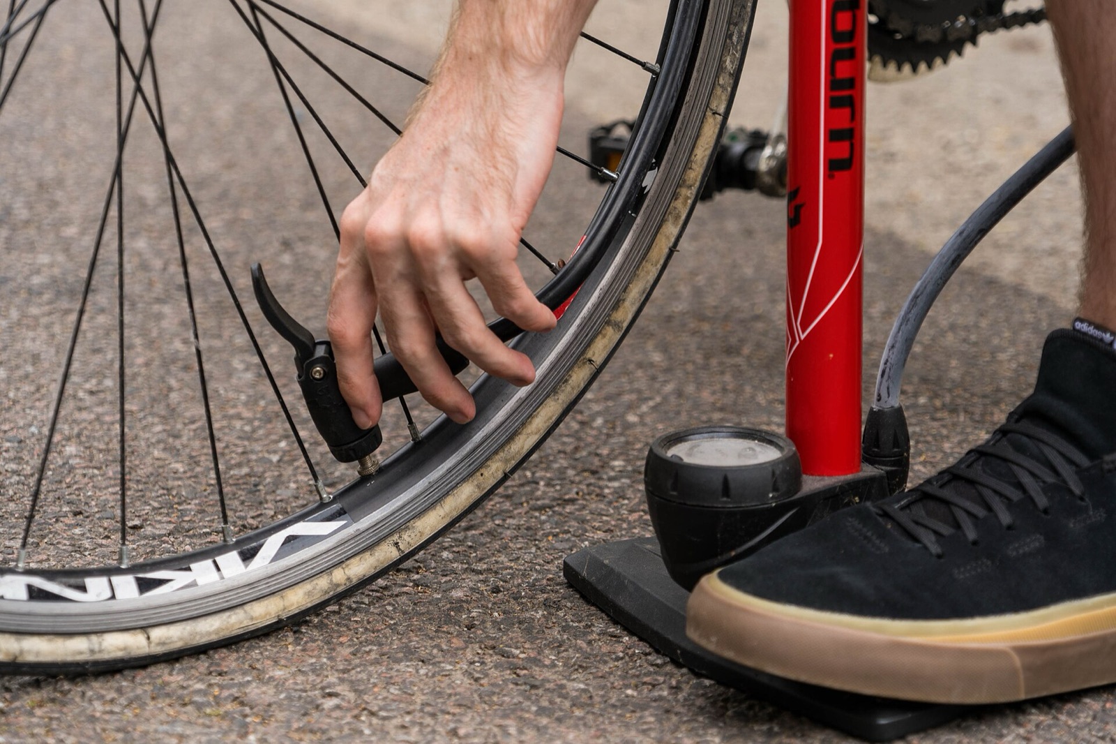 A person using a floor pump to push air into a bicycle tyre.