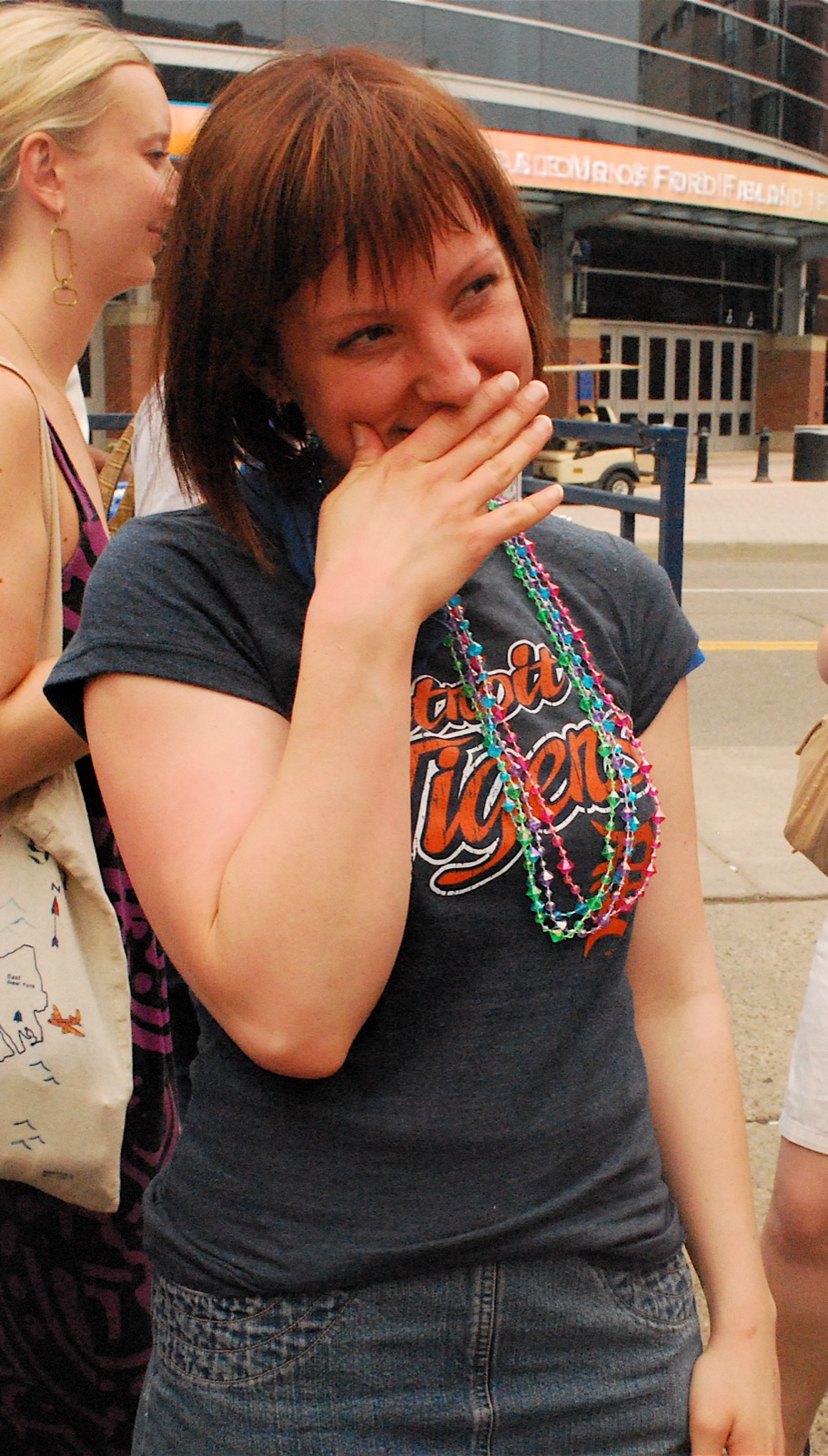 A young woman covering her mouth and smiling bashfully, caught in an embarrassed moment.