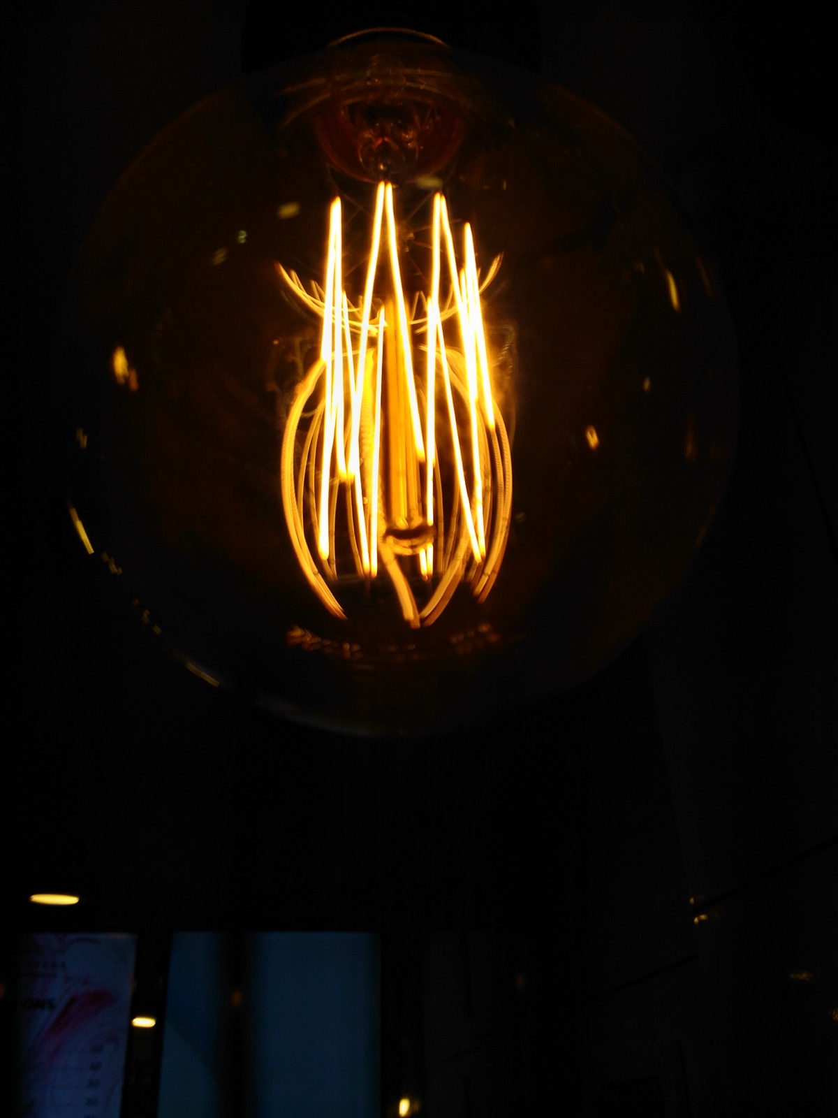 A glowing incandescent bulb with its coiled filament shining bright orange