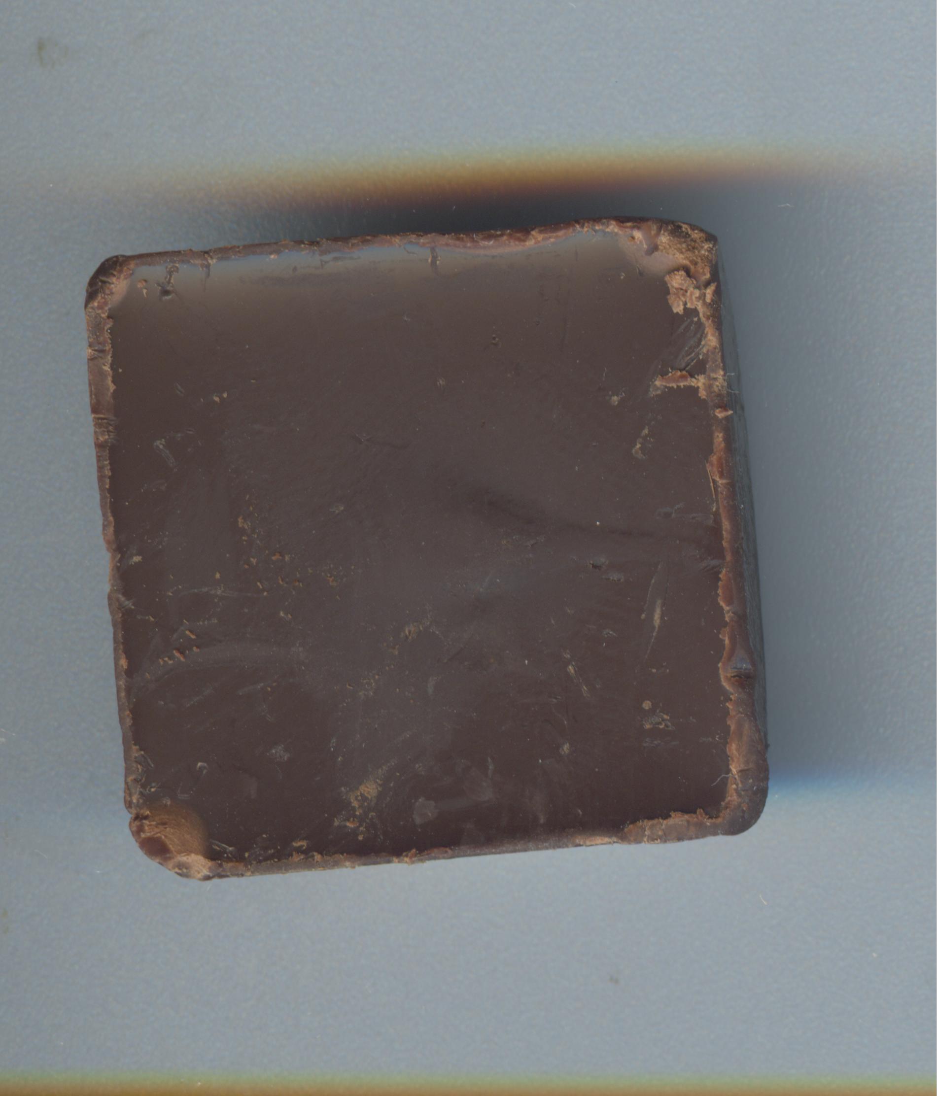 A single square of dark chocolate, its edges just beginning to soften and lose their sharpness.
