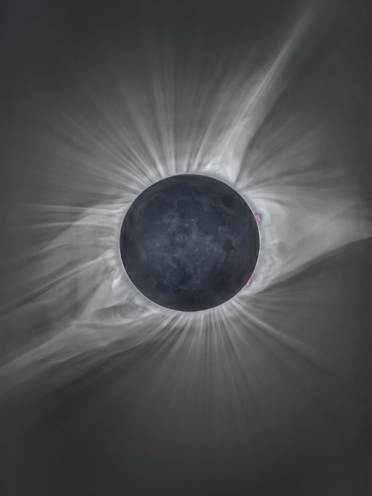 A total solar eclipse showing the Suns white corona streaming out around the dark Moon