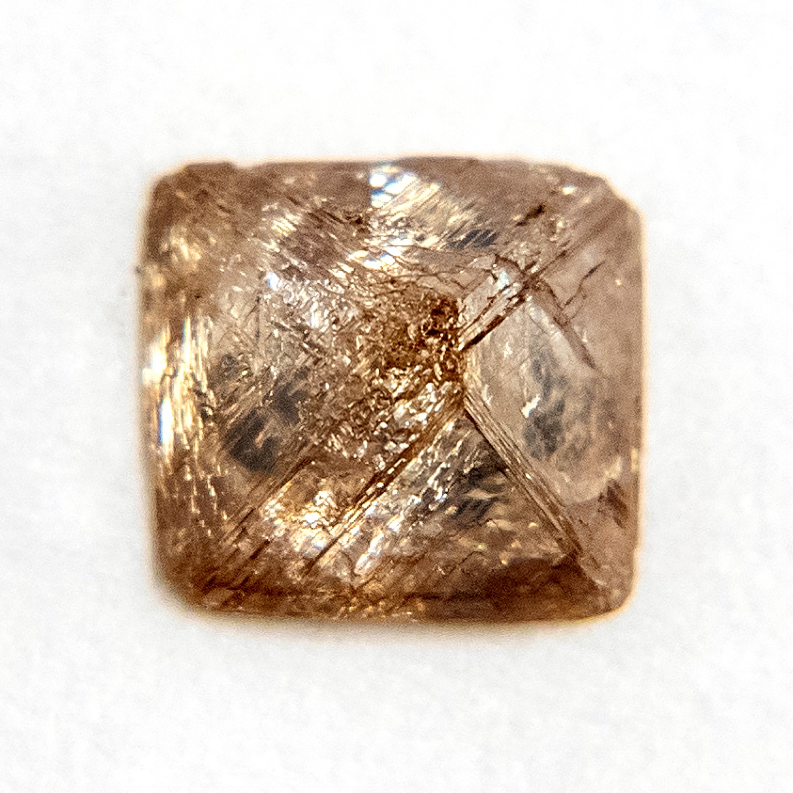 A raw, uncut diamond crystal, pure carbon locked into a rigid, glassy crystal shape.