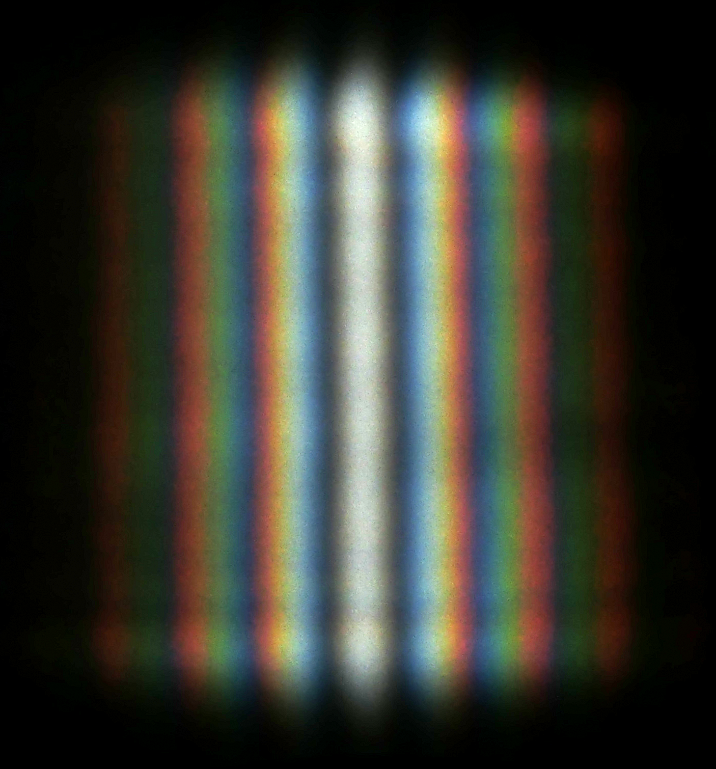 A real double-slit pattern: bright coloured stripes with dark gaps between them, the tell-tale sign of waves adding up and cancelling out