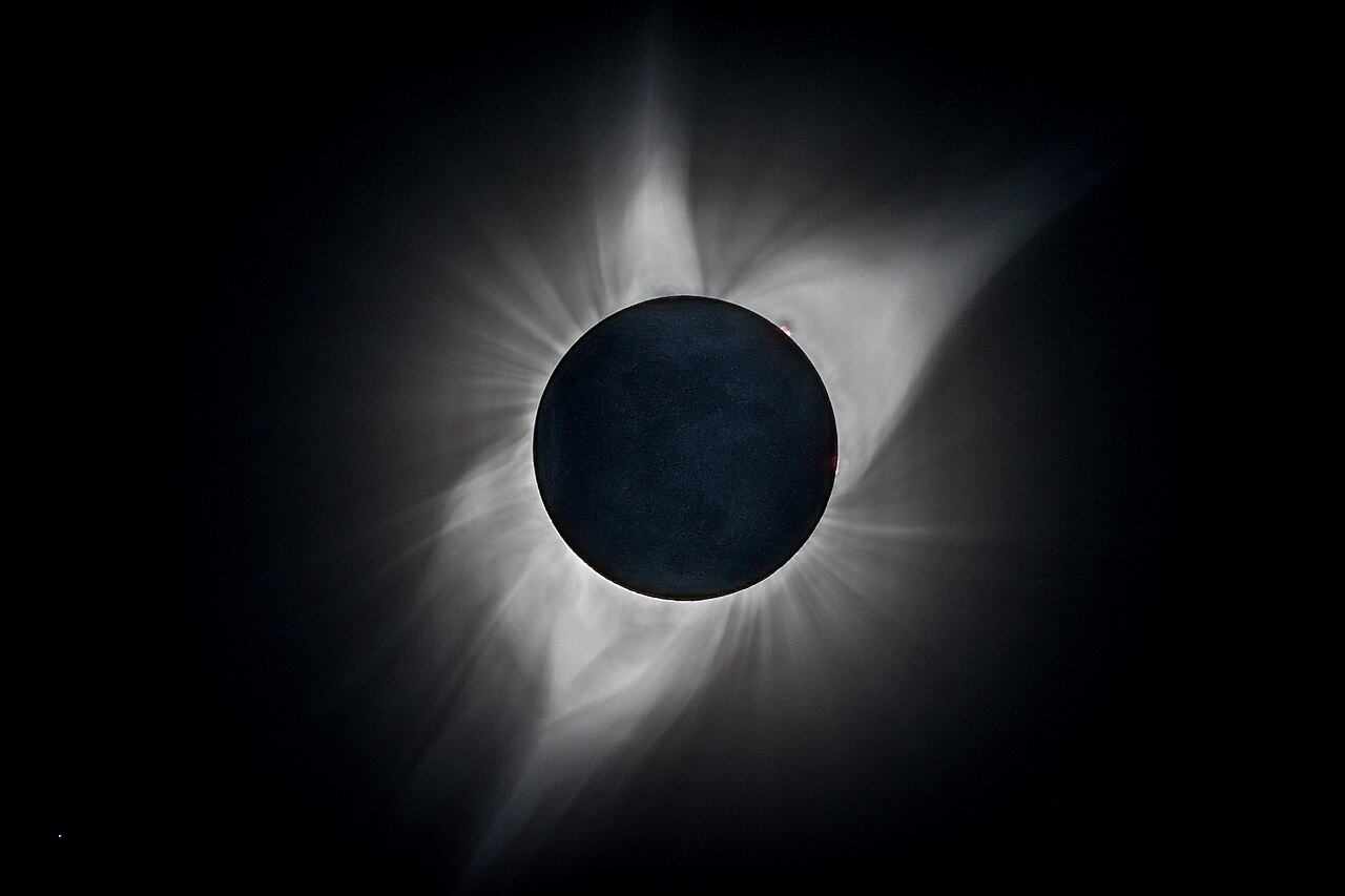 A total solar eclipse, the Moon blocking the Sun, with the glowing corona around it.