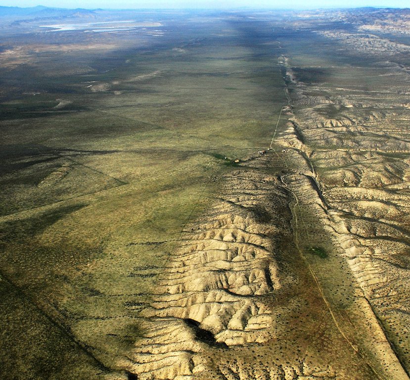 An aerial view of the San Andreas Fault running as a long straight scar across the Carrizo Plain, with ridges offset along its line