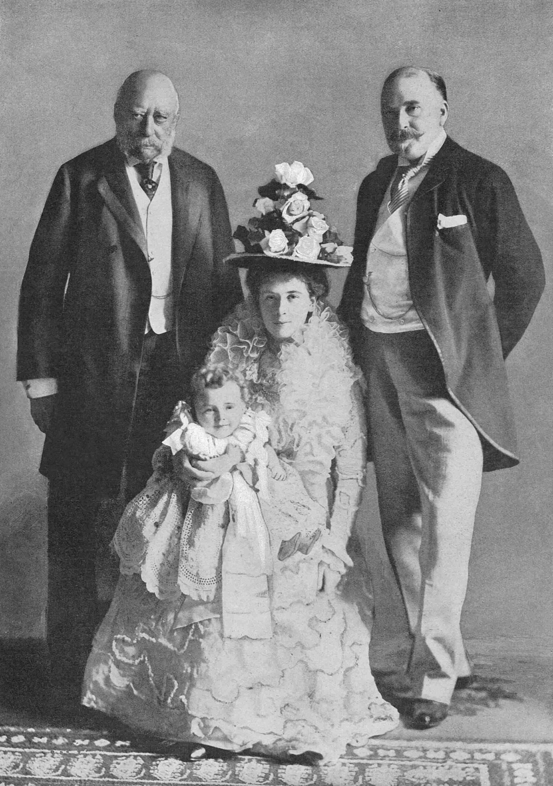 A formal Victorian photograph of four generations of one family posed together, from a small child to an elderly man.