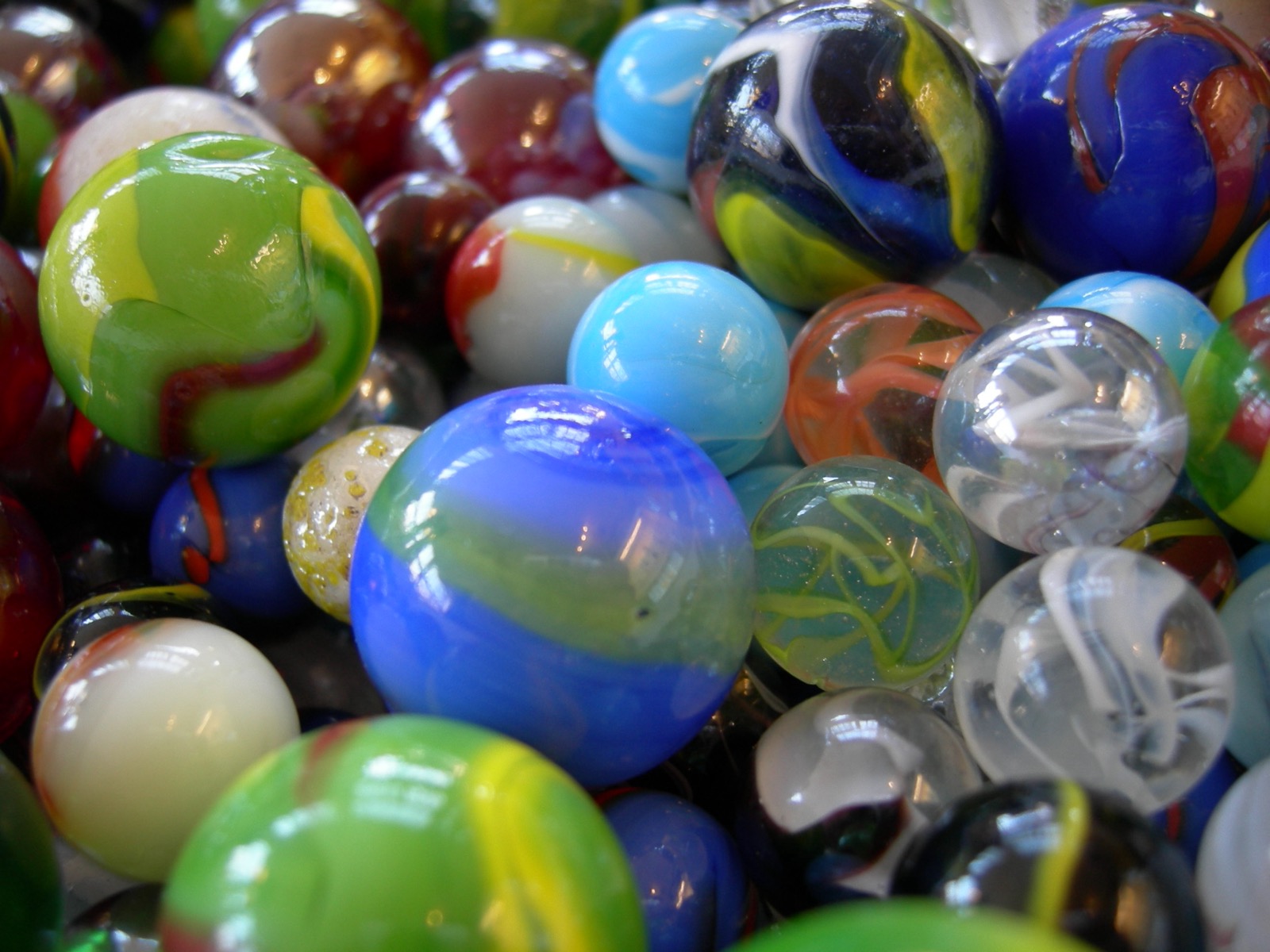 A pile of colourful glass marbles, smooth and rounded with no crystal faces, everyday amorphous glass.