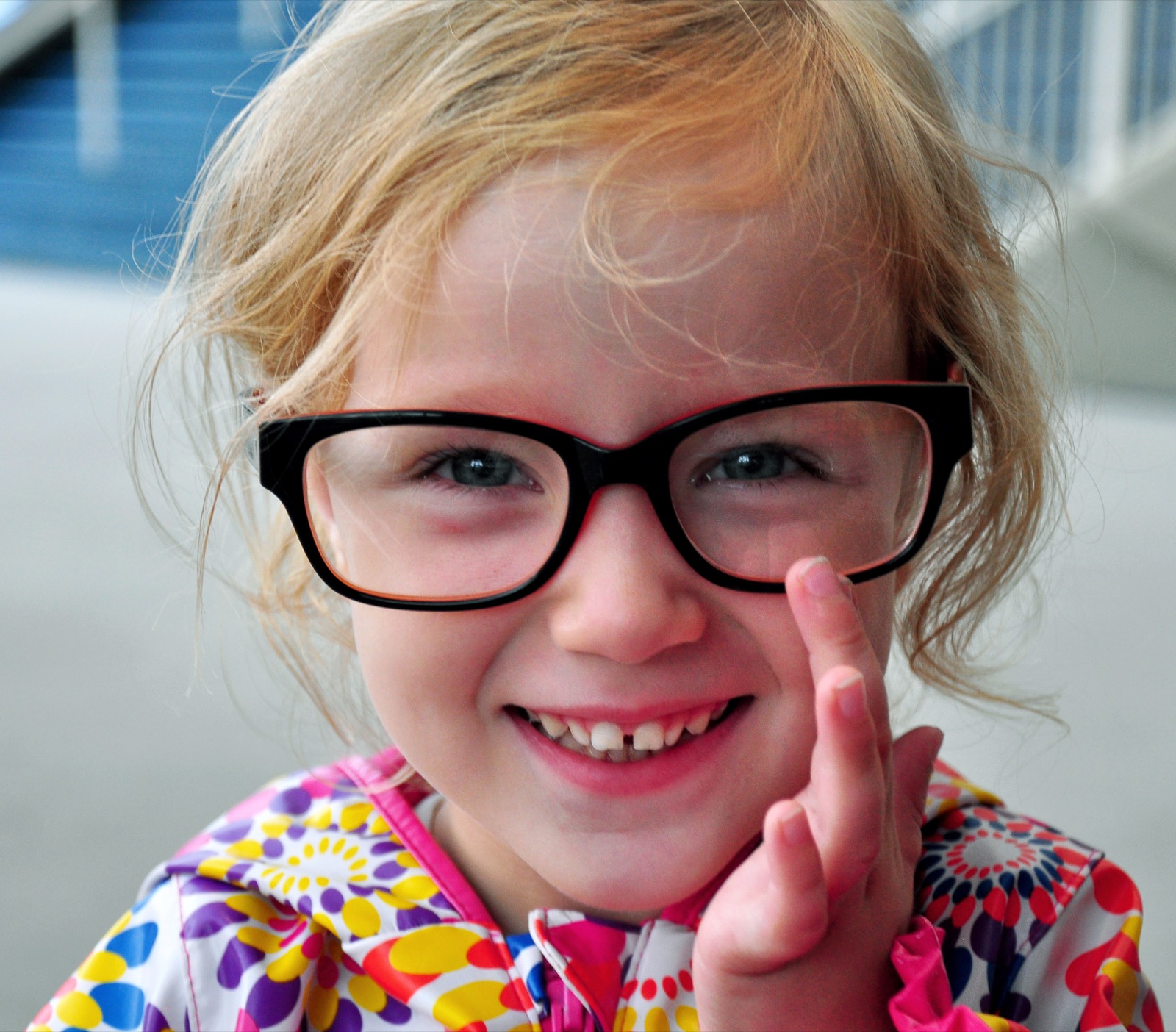 A cheerful child wearing glasses and smiling, lenses that bend light so the picture lands sharply on the retina.
