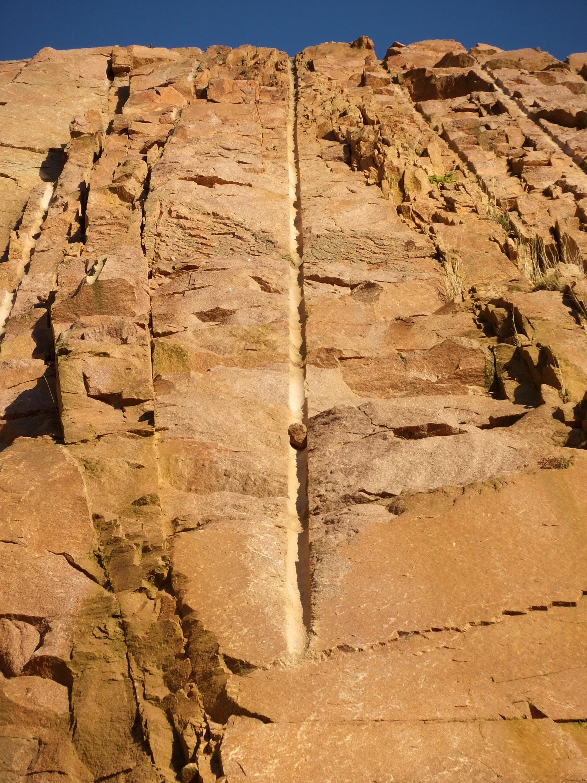 A great face of pink granite in a quarry, rock that began as molten stone deep underground and cooled slowly into crystals