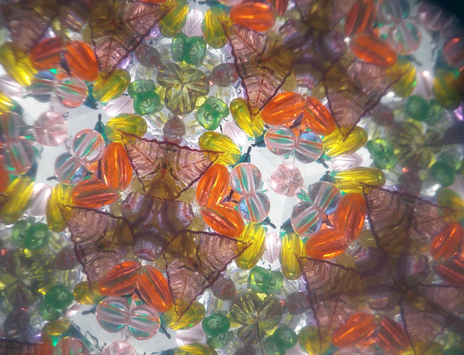 The colourful, symmetrical pattern of beads seen through a kaleidoscope, repeated again and again by its mirrors.