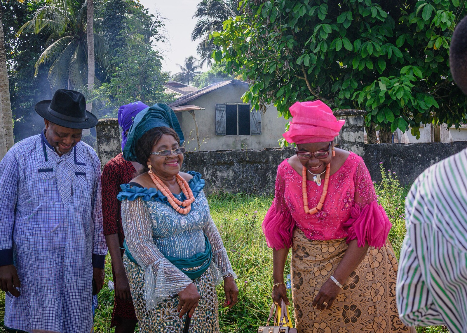 A group of elders in colourful dress laughing together warmly at a celebration.