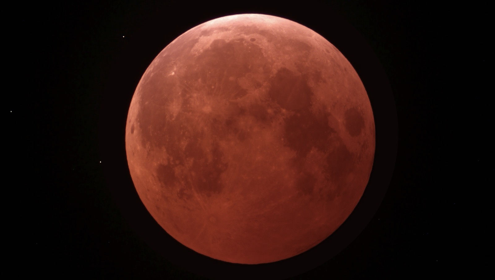 A total lunar eclipse: the full Moon glowing a deep coppery red as it sits in Earth's shadow, a 'blood Moon'.