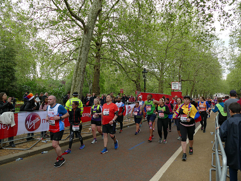 Runners on a tree-lined London road near the end of a marathon, with a sign reading 800m to go
