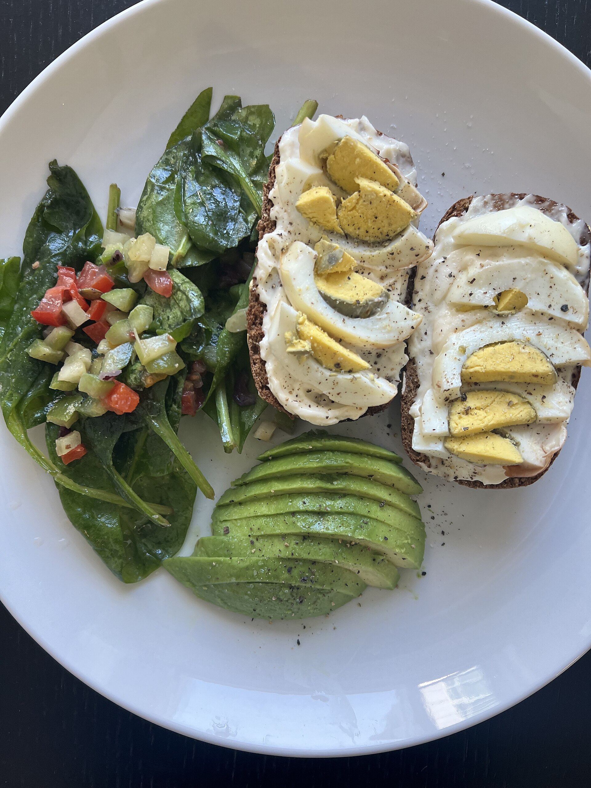 A breakfast plate with sliced boiled egg on toast, avocado and salad, everyday food that many children with an early egg allergy go on to eat