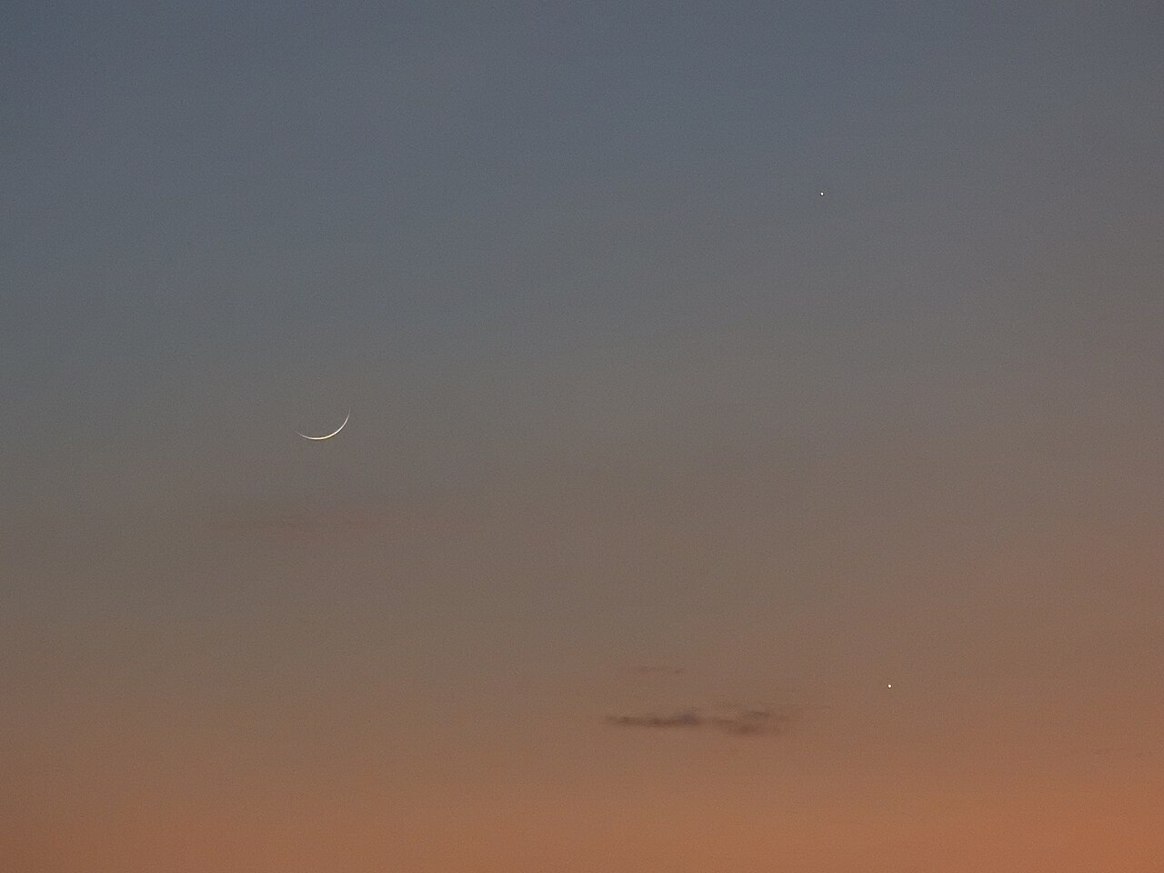 A thin crescent Moon at dusk with two bright star-like points nearby, the planets Venus and Jupiter