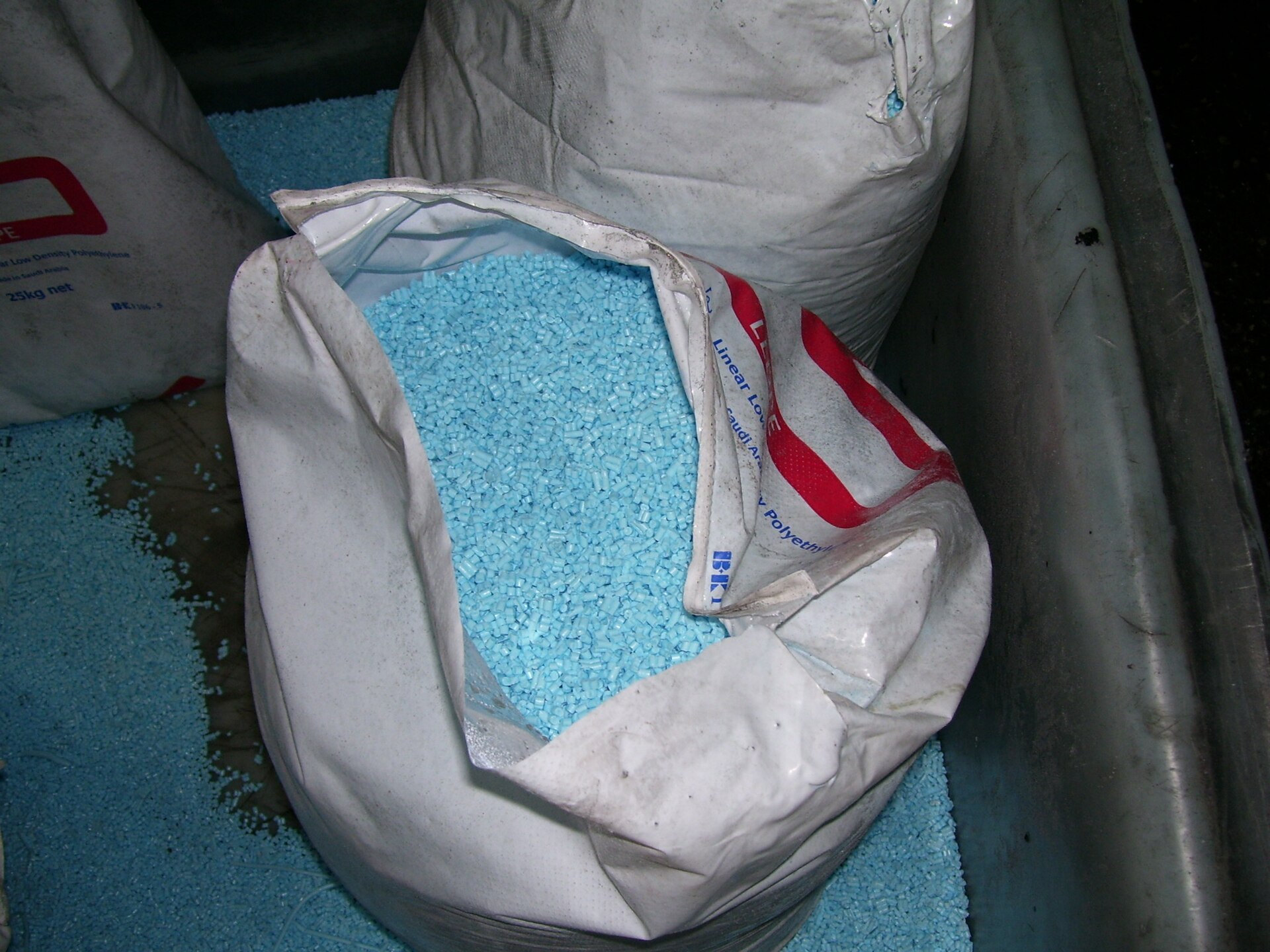 Open sacks of small pale blue plastic pellets, the raw beads that factories melt to make plastic objects.