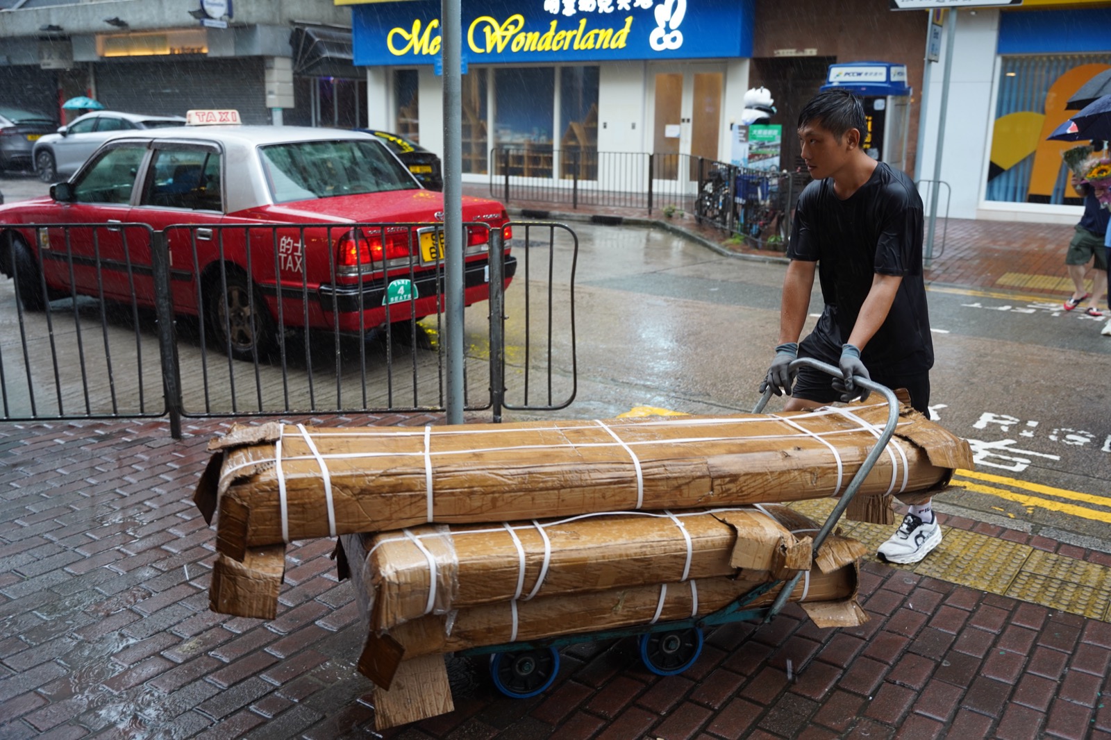 A person pushing a heavy, loaded handcart along a street.