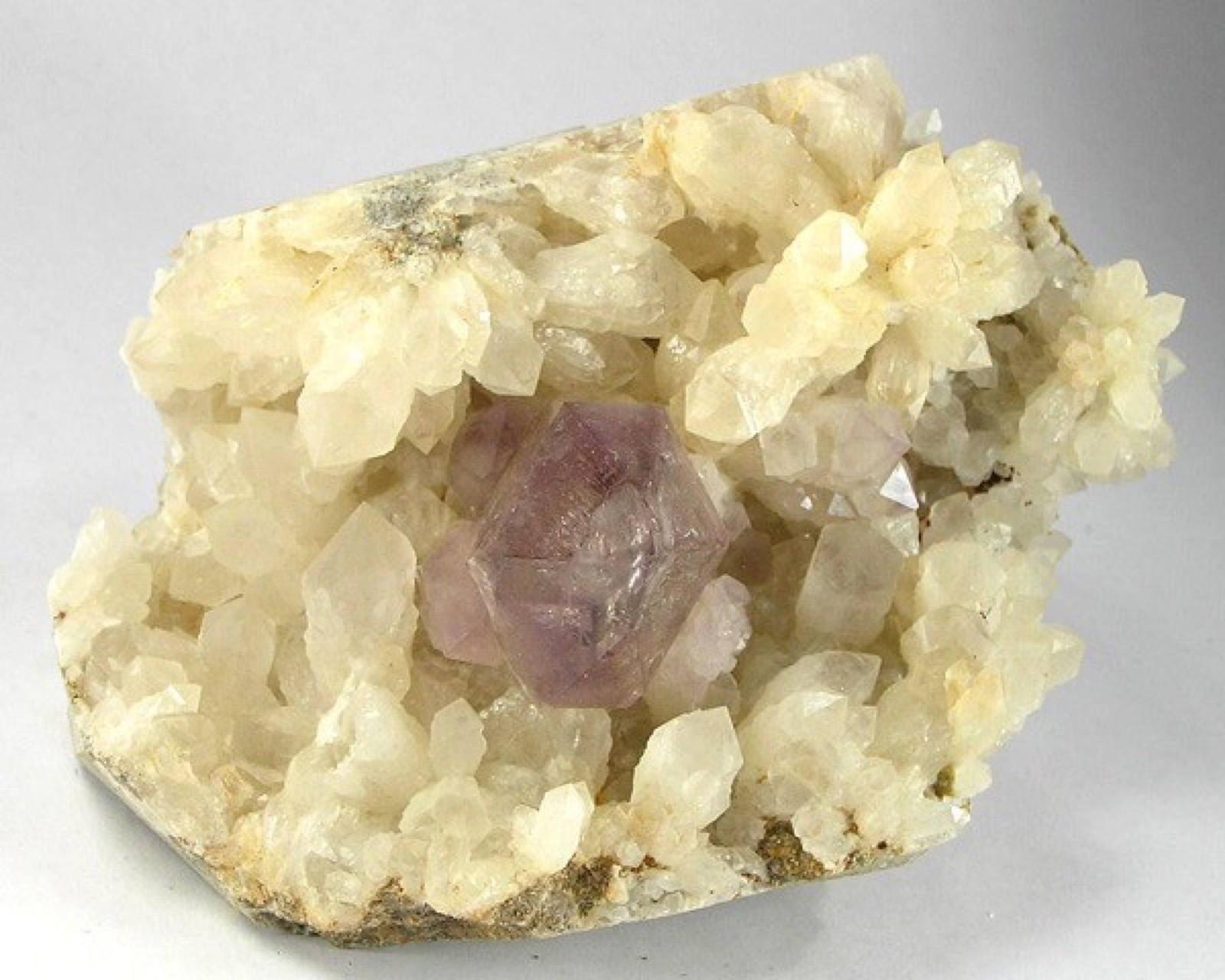 A cluster of quartz crystals around a purple amethyst point, each crystal showing flat faces and sharp geometric edges.