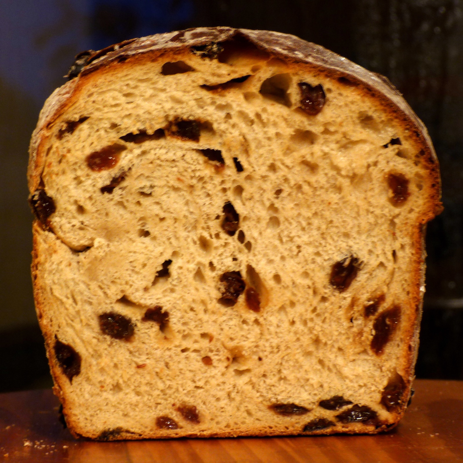 A cut loaf of raisin bread with raisins spread through the crumb