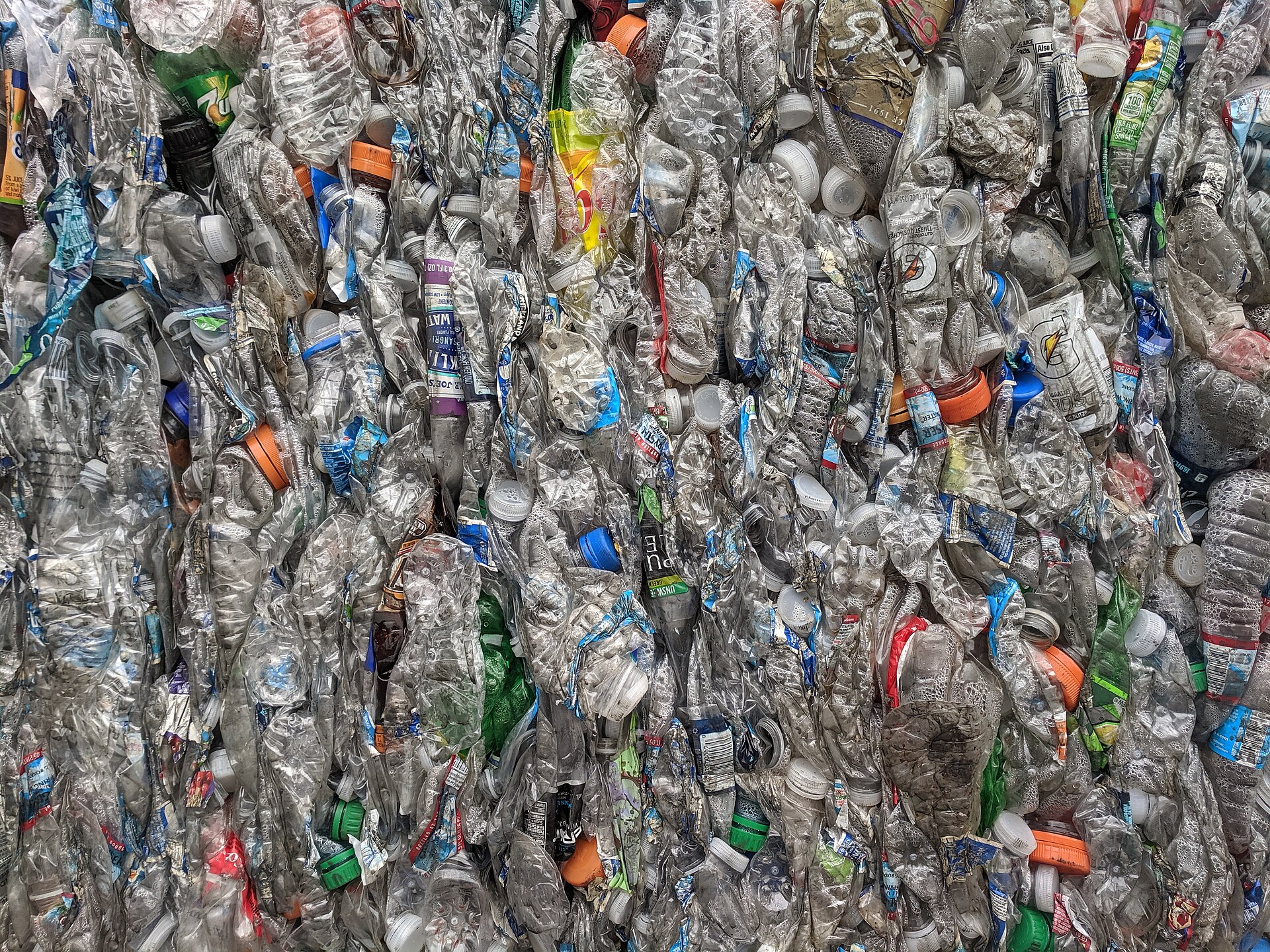 A huge compressed bale of crushed clear plastic drinks bottles at a recycling plant.