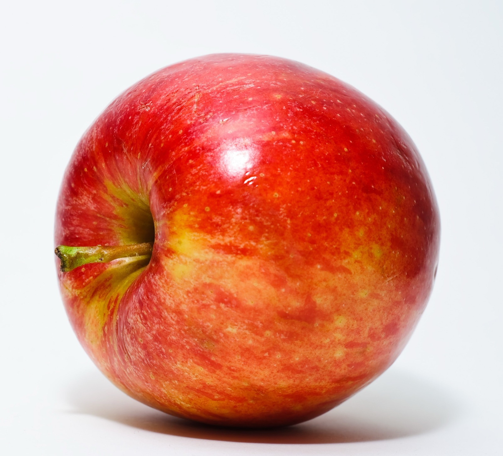 A shiny red apple on a plain white background.