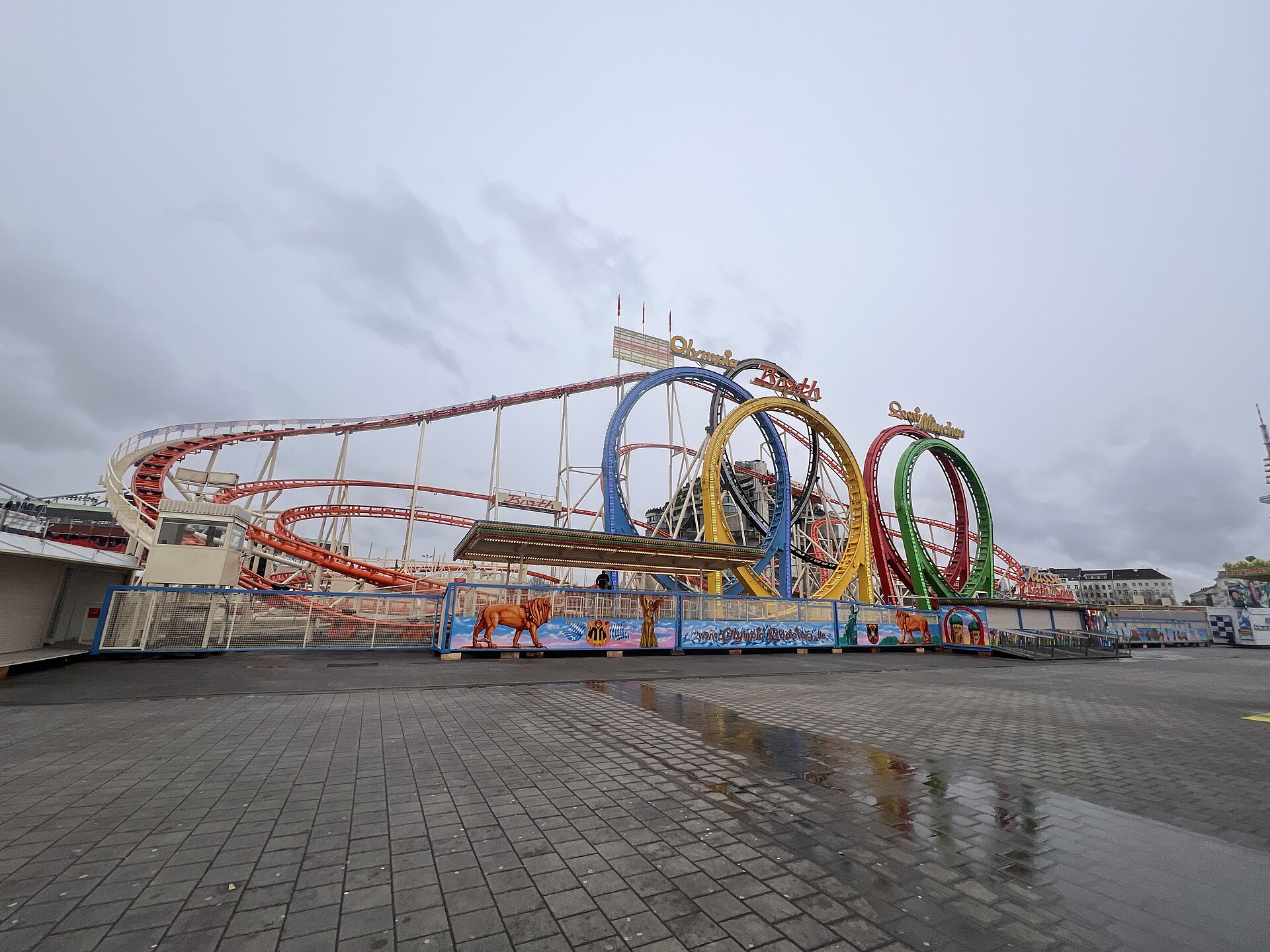 A fairground rollercoaster with five tall vertical loops in different colours, where the carriages travel upside down over the top.