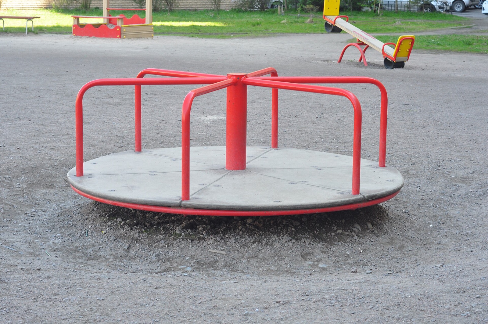 A red playground roundabout, the kind you spin round and round on.