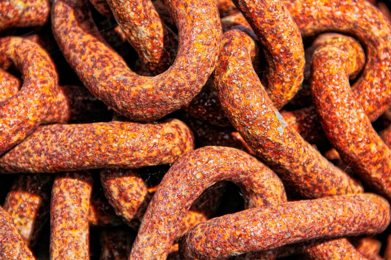 Close-up of heavy iron chain links covered in flaky orange-brown rust.