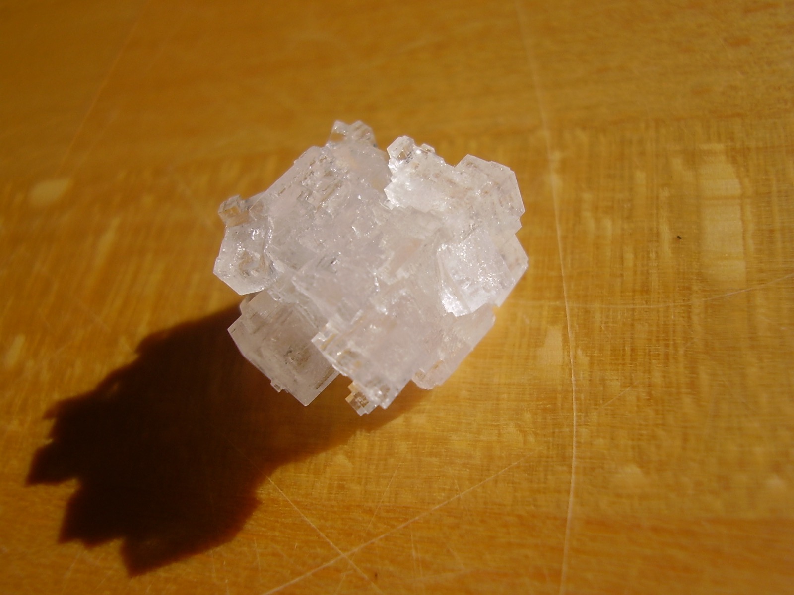 A home-grown salt crystal, translucent cubes stacked together with flat faces and right-angle corners.