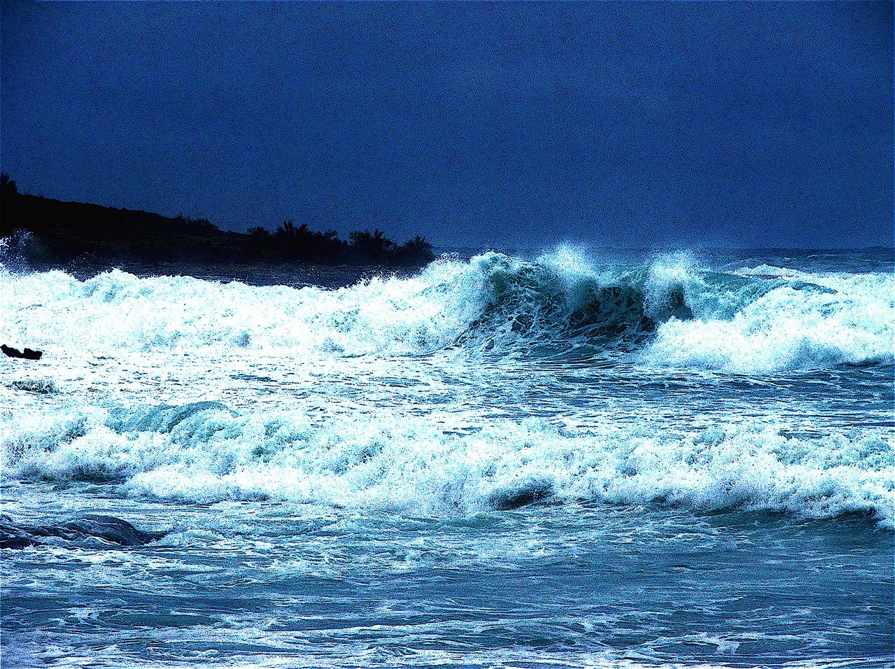Lines of white-capped sea waves rolling in one behind another towards the shore