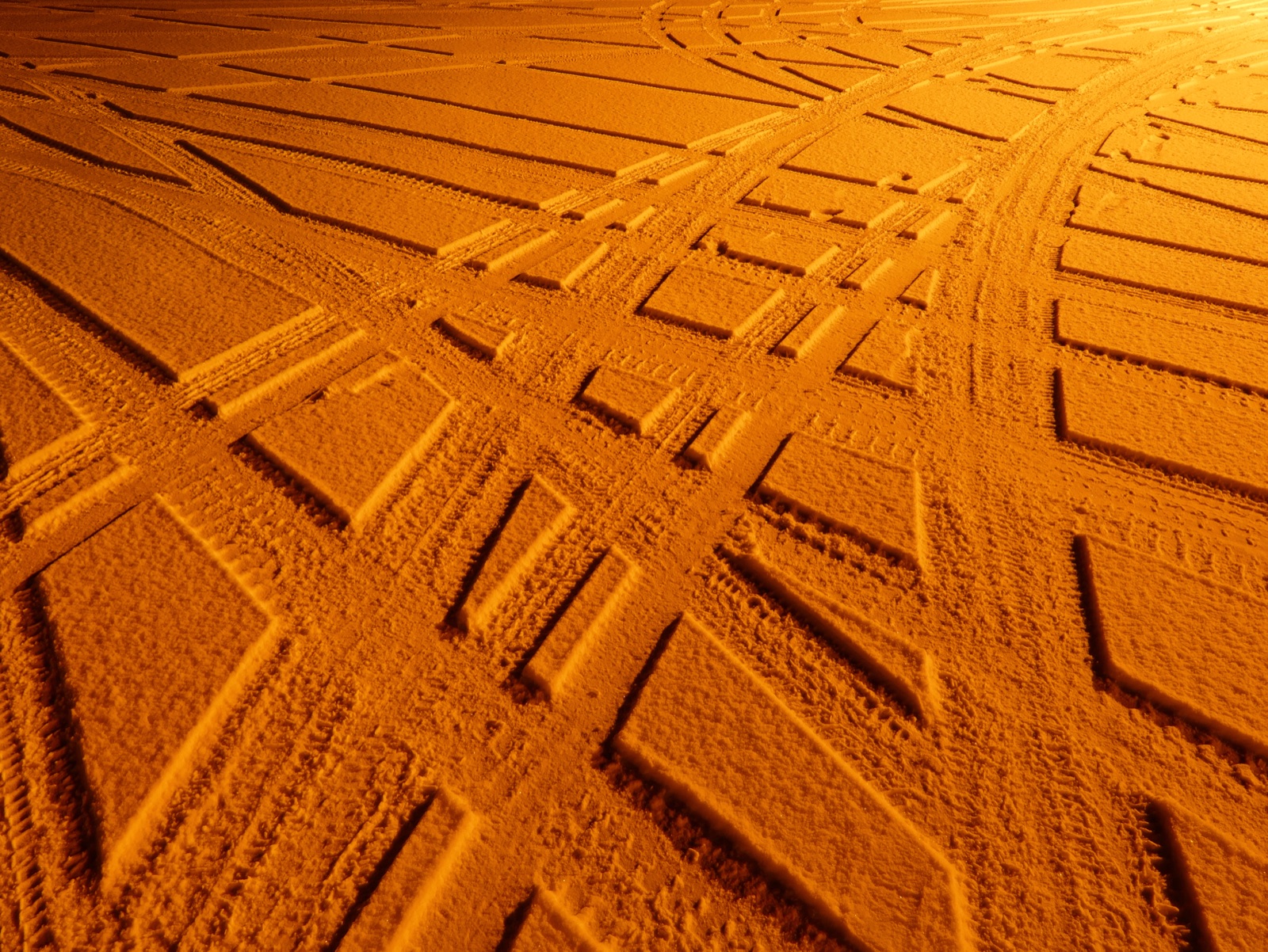 Snow with tyre tracks, lit entirely orange by a sodium street lamp so every other colour has drained away.