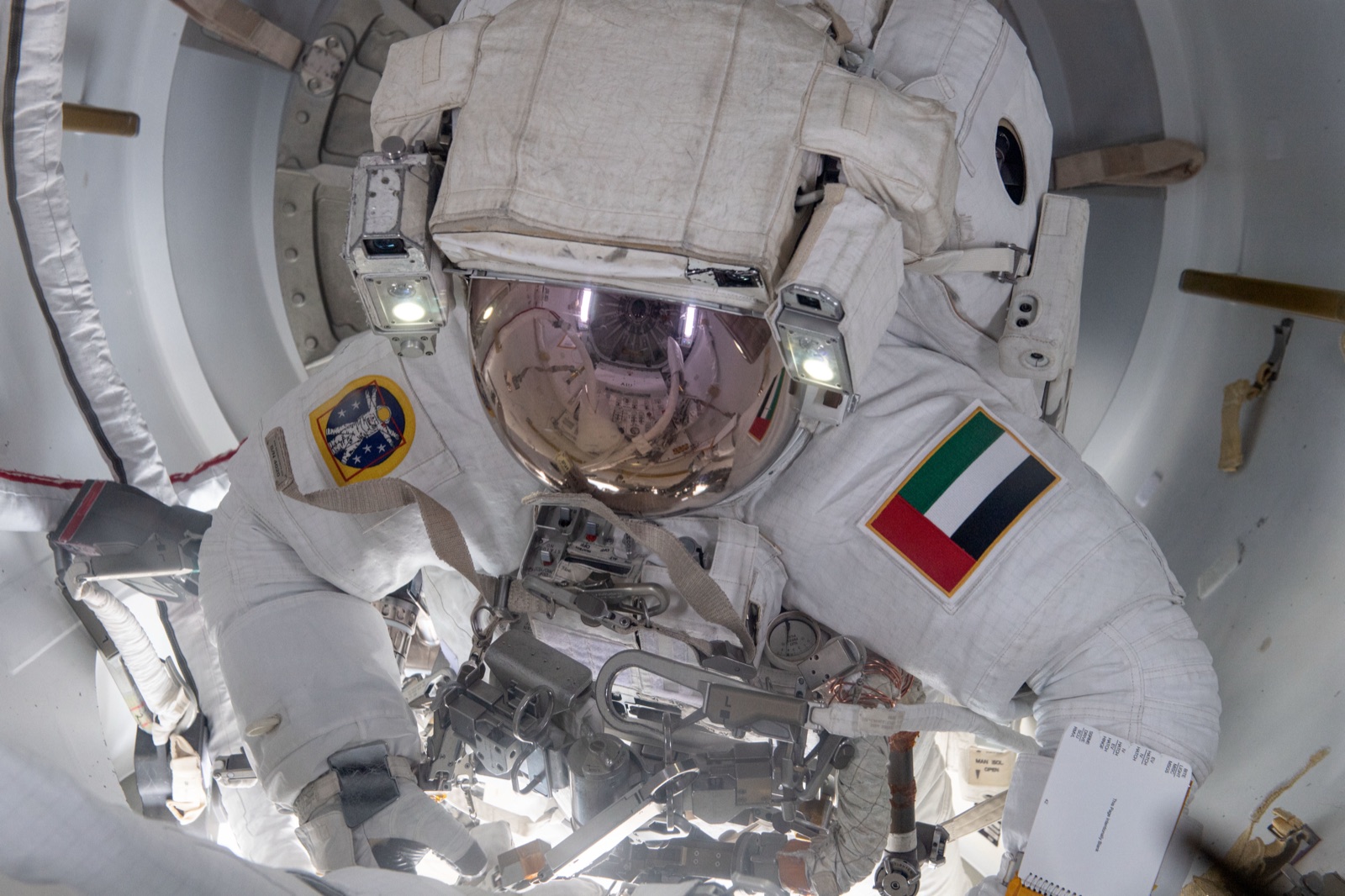 An astronaut in a bulky white spacesuit and mirrored helmet, ready for a spacewalk.