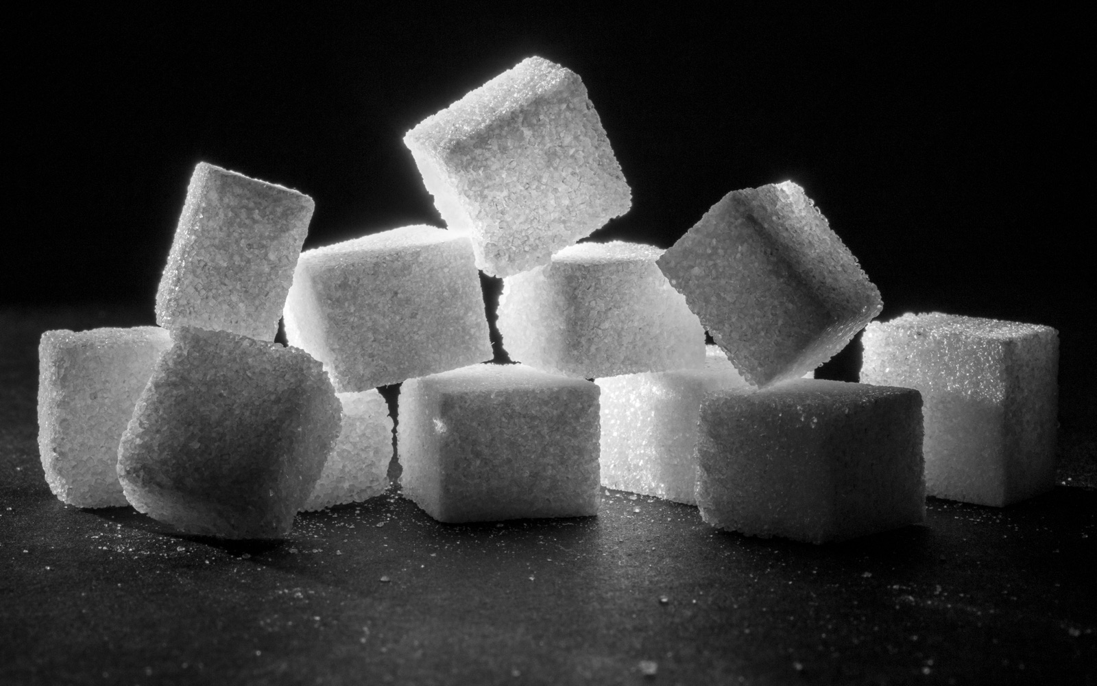 A pile of white sugar cubes lit against a dark background