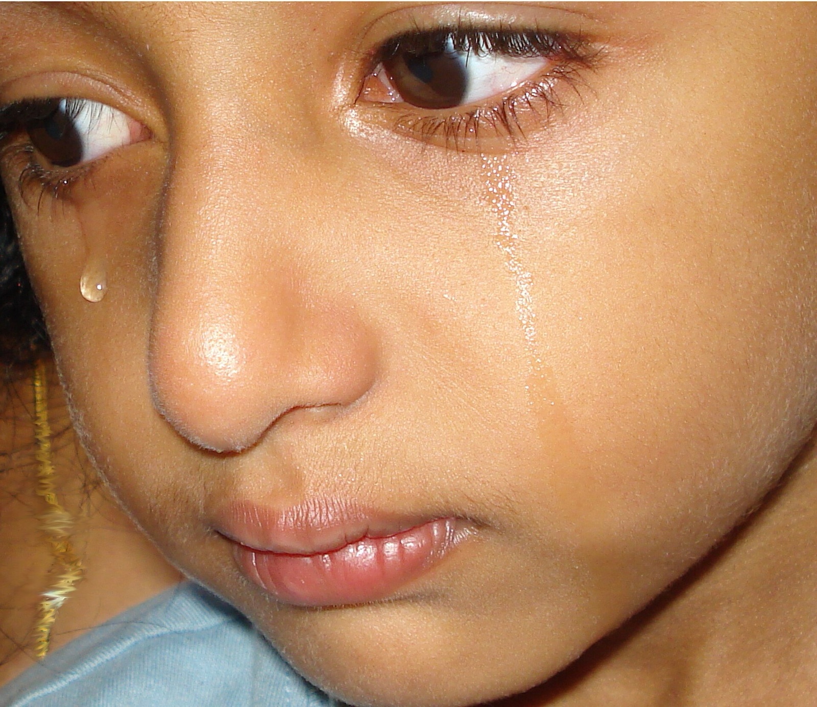 A child’s face with tears rolling down both cheeks.