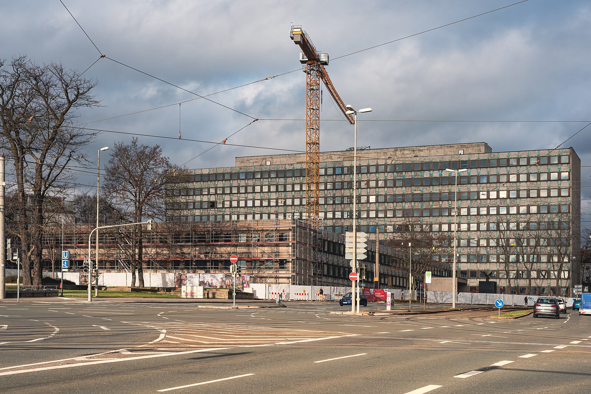 A tower crane standing over a building site, its long jib reaching out one way and a short counter-jib with weights the other