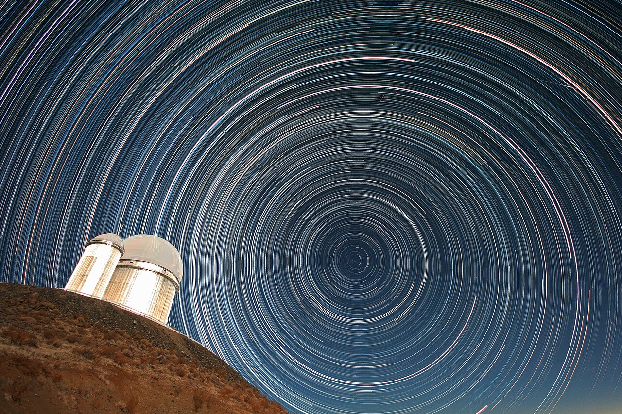 Star trails circling over a telescope dome at night.