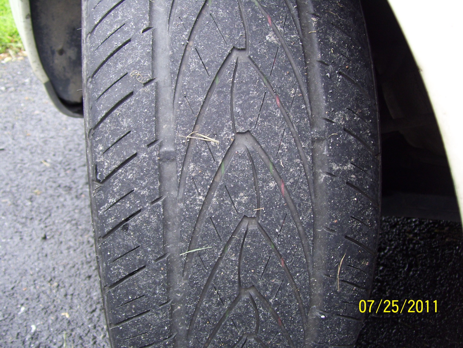 Close-up of a car tyre showing the grooves carved into its tread.