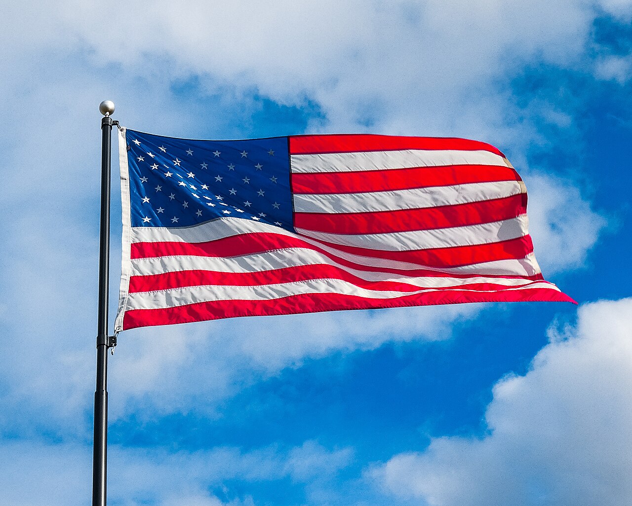 A flag stretched out and rippling in a strong wind.